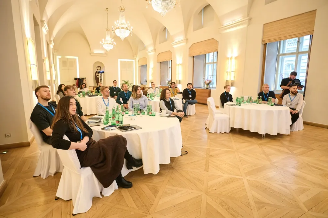 Sala ze żyrandolami i okrągłymi stołami, przy których siedzą uczestnicy spotkania Usercentrics Advisory Board w Pradze